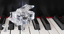 A miniature crystal piano resting on a piano keyboard